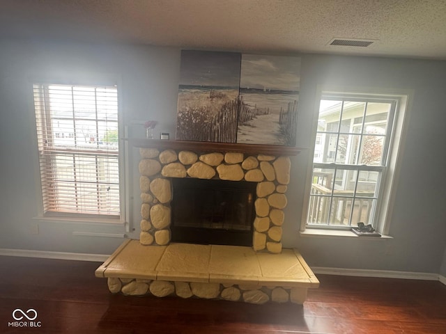 317 Legacy Blvd, Greenwood, IN 46143 - room details featuring a fireplace, a textured ceiling, baseboards, wood finished floors, and visible vents