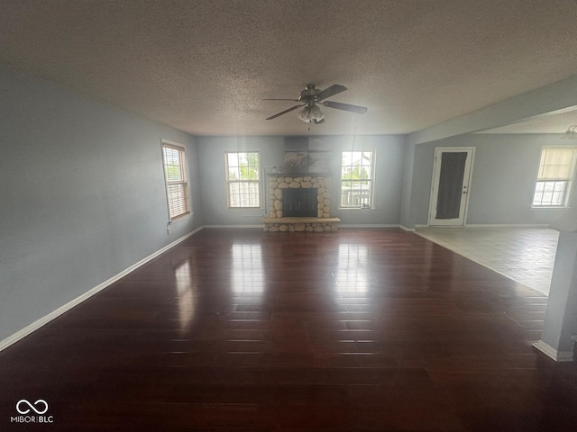 317 Legacy Blvd, Greenwood, IN 46143 - unfurnished living room featuring ceiling fan, a stone fireplace, a textured ceiling, wood finished floors, and baseboards