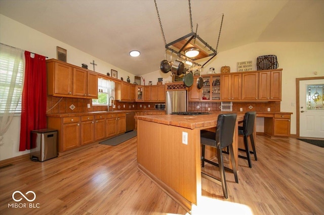 11815 E Pocahontas Dr, Greencastle, IN 46135 - kitchen featuring appliances with stainless steel finishes, a kitchen island, brown cabinets, vaulted ceiling, and light wood finished floors