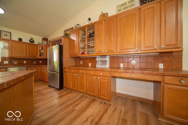 11815 E Pocahontas Dr, Greencastle, IN 46135 - kitchen featuring appliances with stainless steel finishes, tile counters, lofted ceiling, light wood-style flooring, and glass insert cabinets