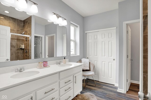 5580 Pintail Ln, Greenwood, IN 46143 - bathroom with tiled shower, double vanity, and wood finished floors