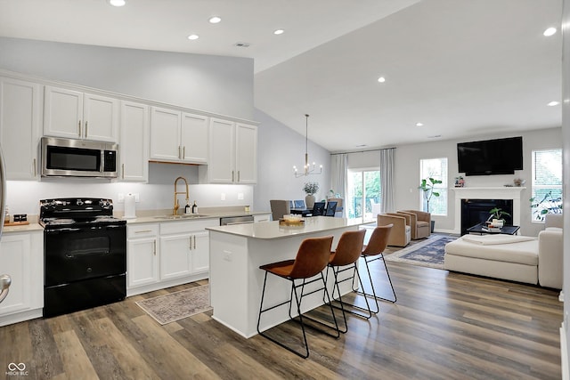 5580 Pintail Ln, Greenwood, IN 46143 - kitchen with stainless steel microwave, black electric range, a sink, a center island, and white cabinetry