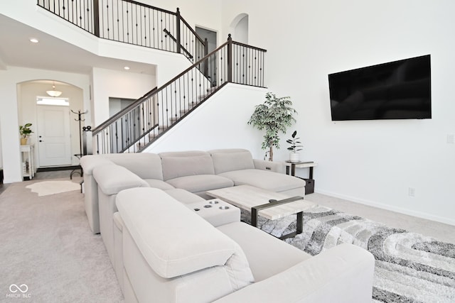 living area with arched walkways, a high ceiling, baseboards, and carpet flooring