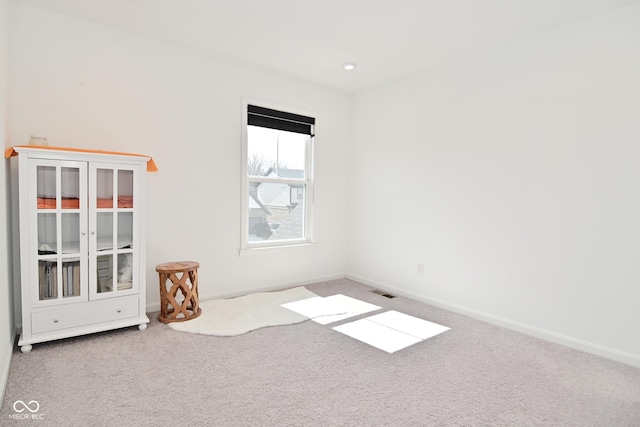 carpeted empty room featuring baseboards and visible vents