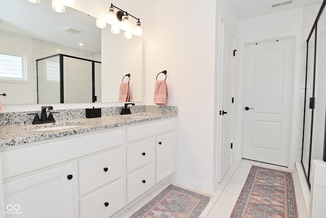 bathroom with double vanity, a sink, a stall shower, and tile patterned flooring