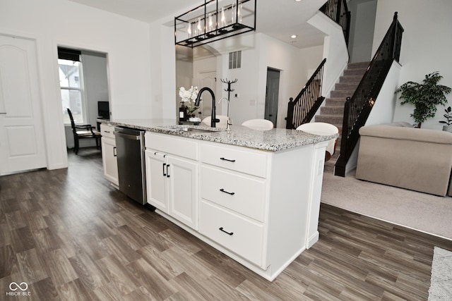 kitchen with stainless steel dishwasher, dark wood-style floors, white cabinets, light stone counters, and a sink