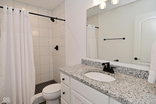 full bathroom with vanity, a tile shower, and toilet
