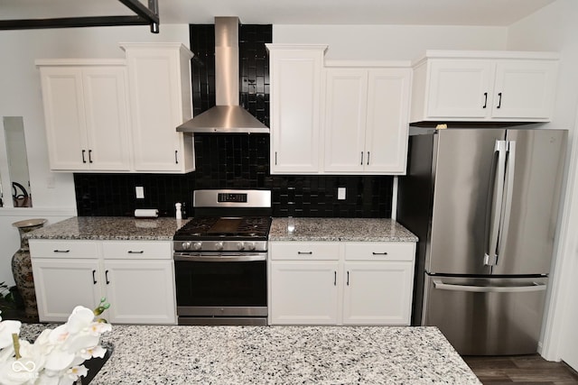 kitchen featuring white cabinetry, appliances with stainless steel finishes, light stone counters, and wall chimney exhaust hood