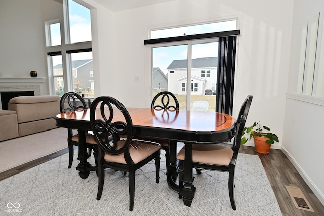 dining space featuring visible vents, baseboards, wood finished floors, and a fireplace