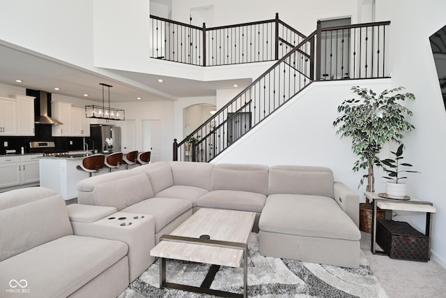 living area with arched walkways, baseboards, recessed lighting, and a towering ceiling