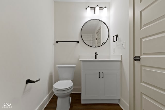 half bathroom featuring baseboards, vanity, toilet, and wood finished floors