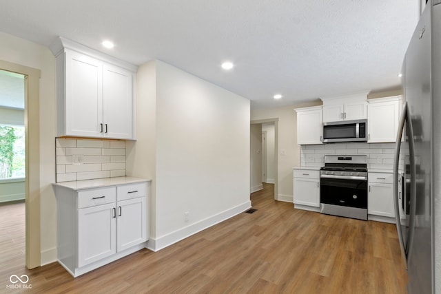 kitchen featuring light countertops, tasteful backsplash, light wood-style floors, and stainless steel appliances