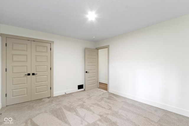 unfurnished bedroom with baseboards, carpet flooring, and a closet