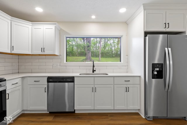 kitchen with a sink, light countertops, stainless steel appliances, white cabinetry, and backsplash