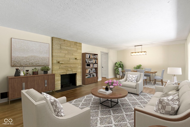 living area with a textured ceiling, baseboards, a stone fireplace, and wood finished floors