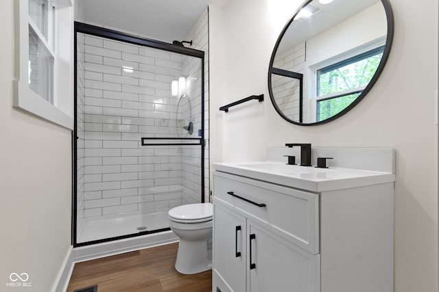 bathroom with toilet, a shower stall, wood finished floors, and vanity