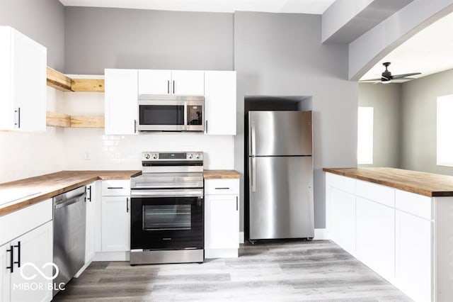 kitchen with butcher block countertops, appliances with stainless steel finishes, open shelves, ceiling fan, and light wood-style floors