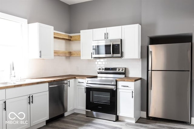 kitchen featuring stainless steel appliances, butcher block counters, a sink, and open shelves