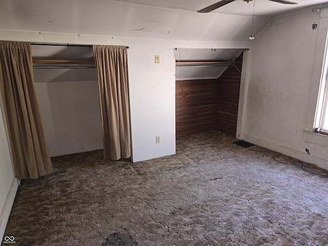 basement featuring a ceiling fan, wood walls, and carpet flooring