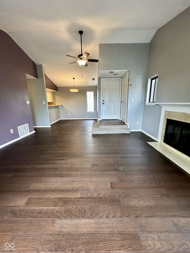 unfurnished living room featuring visible vents, wood finished floors, a fireplace, baseboards, and a ceiling fan