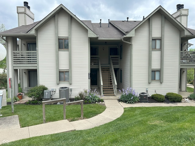 view of front of house featuring cooling unit, stairs, and a front lawn