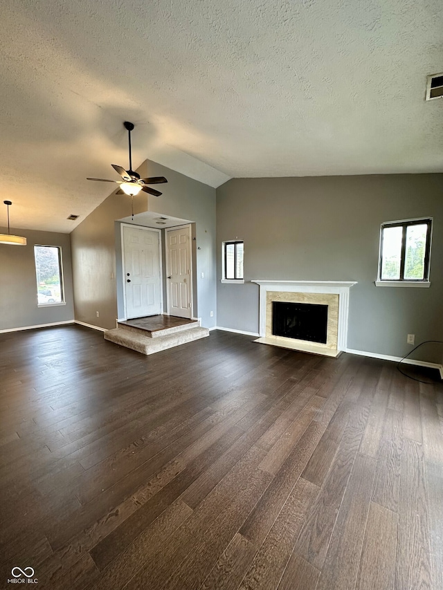 unfurnished living room featuring baseboards, lofted ceiling, a textured ceiling, and dark wood-type flooring