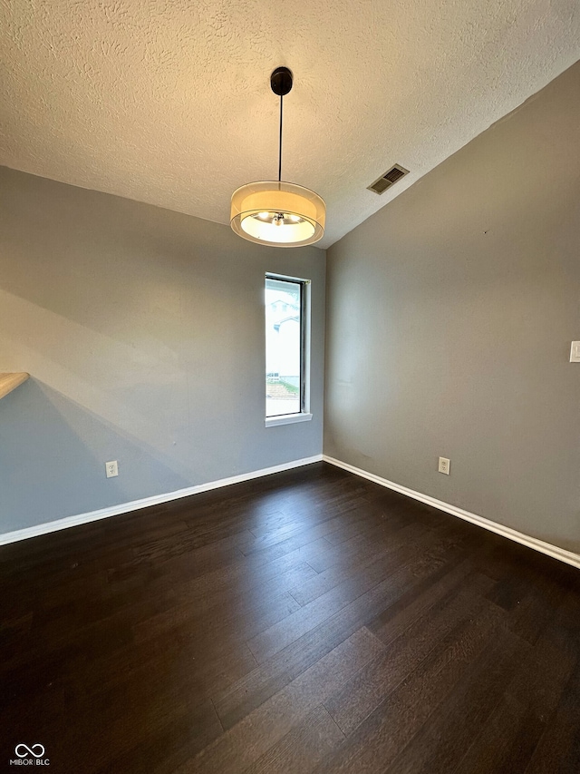 empty room featuring a textured ceiling, baseboards, visible vents, and dark wood-type flooring