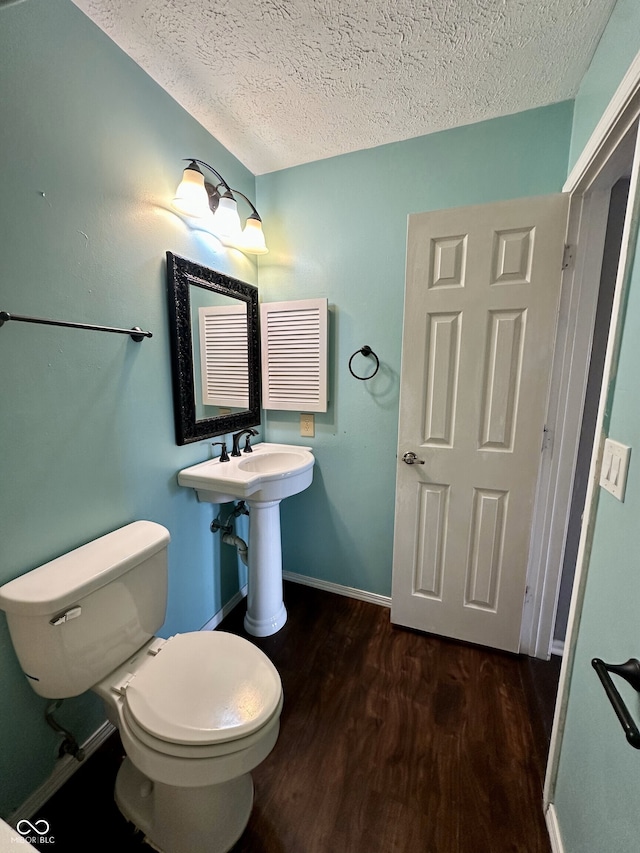 half bathroom featuring baseboards, toilet, a textured ceiling, and wood finished floors