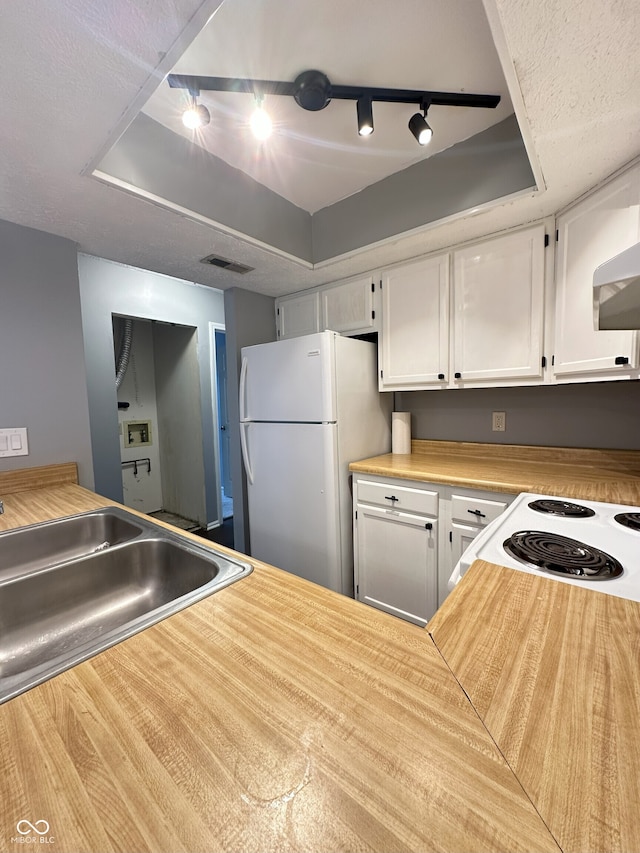 kitchen featuring freestanding refrigerator, white cabinetry, rail lighting, and visible vents