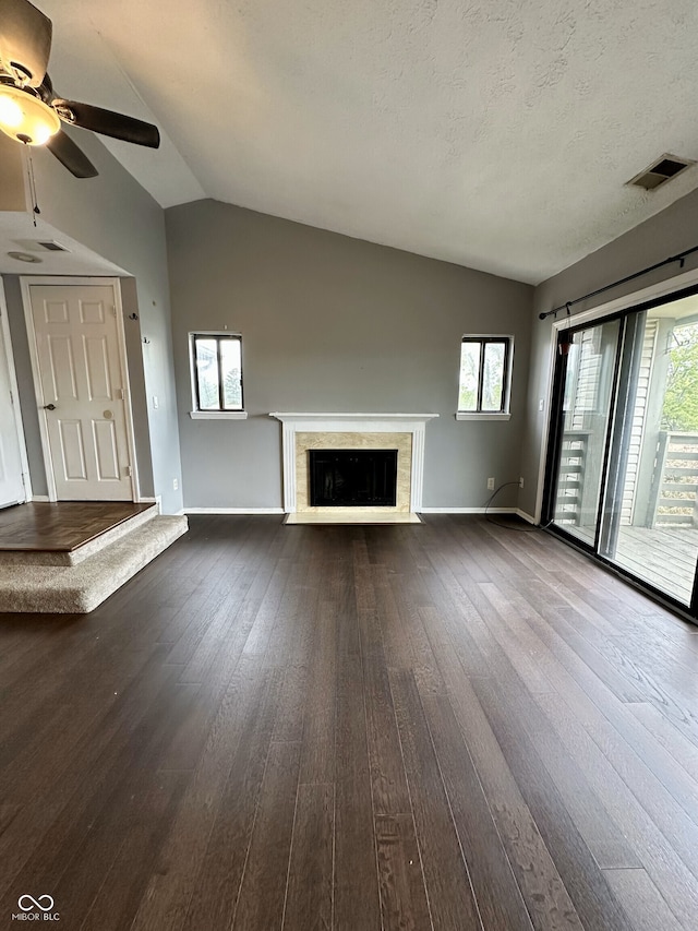 unfurnished living room featuring a ceiling fan, baseboards, dark wood-type flooring, a fireplace with flush hearth, and vaulted ceiling