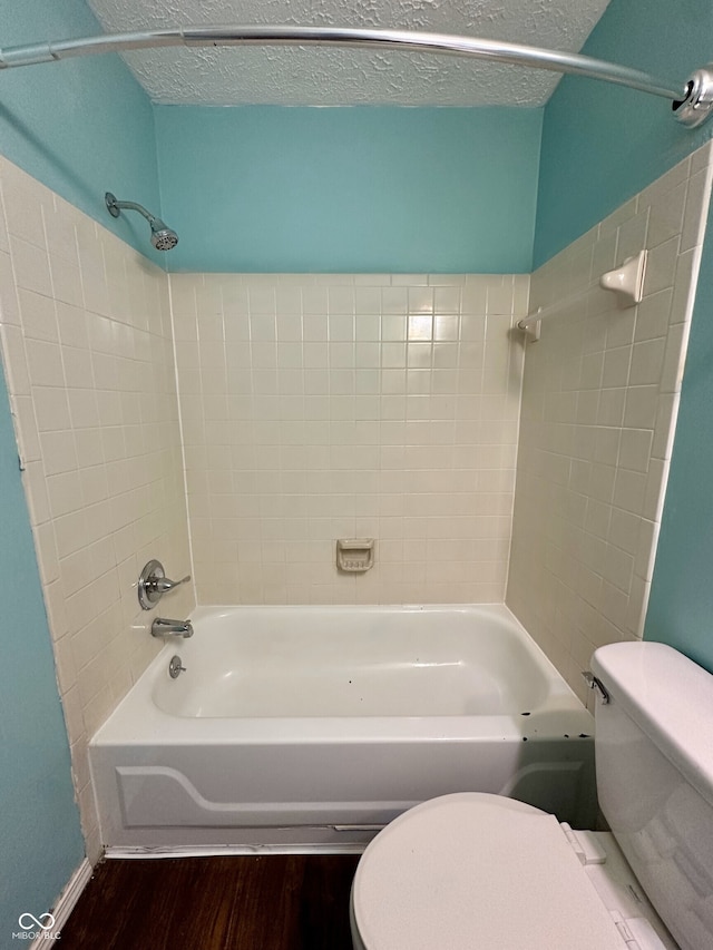 bathroom with bathing tub / shower combination, toilet, and wood finished floors