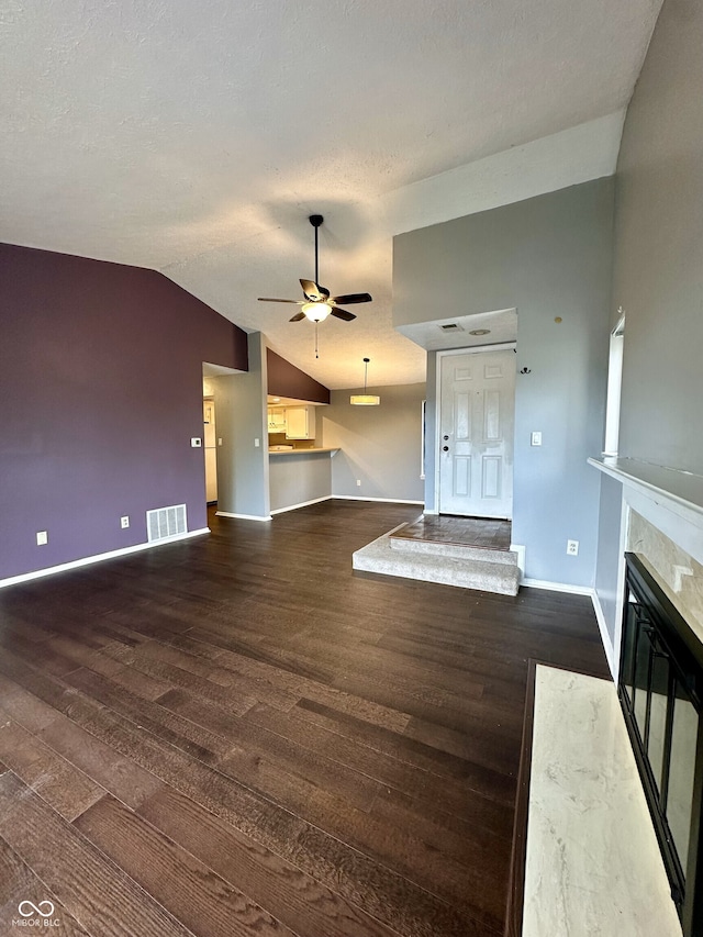 unfurnished living room with baseboards, wood finished floors, vaulted ceiling, and visible vents