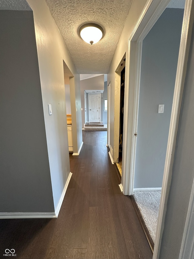 hall featuring baseboards, a textured ceiling, and dark wood-style floors