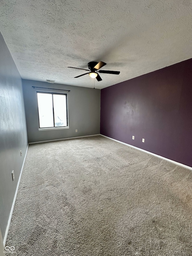 carpeted empty room with baseboards, a ceiling fan, and a textured ceiling