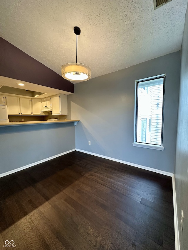 kitchen featuring baseboards, a textured ceiling, dark wood finished floors, and white cabinets