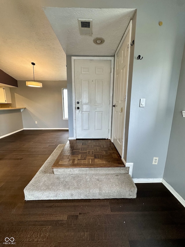 interior space featuring a textured ceiling, baseboards, visible vents, and wood finished floors
