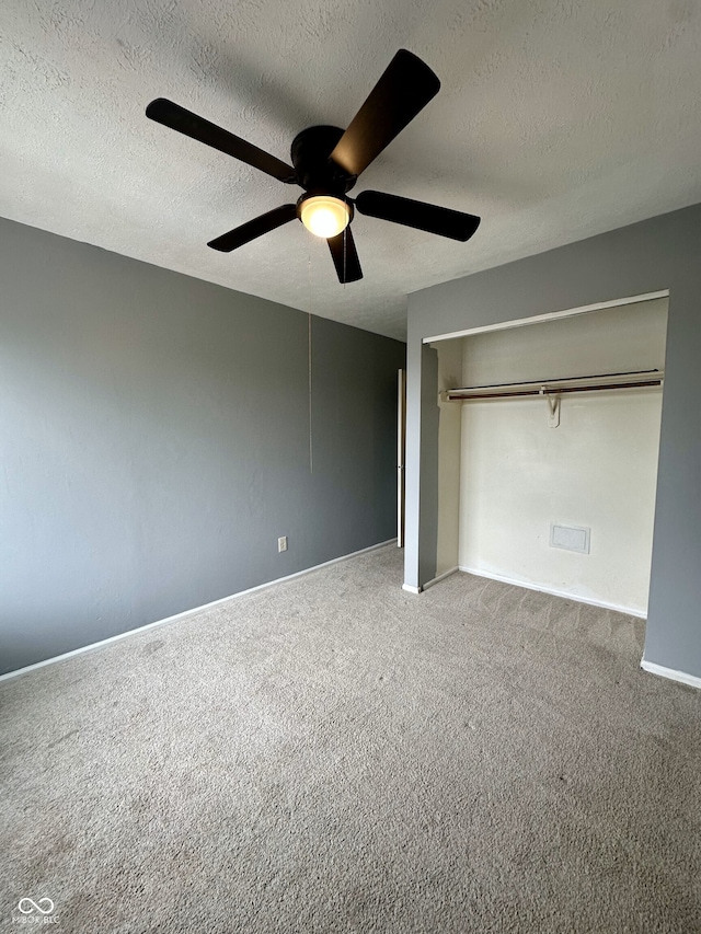 unfurnished bedroom with a closet, a textured ceiling, carpet, and a ceiling fan