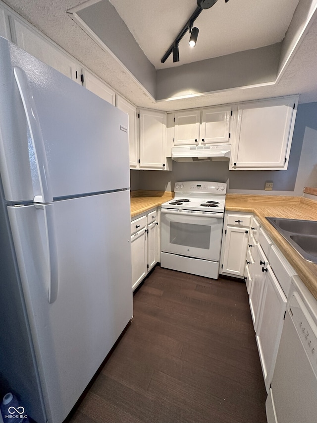 kitchen featuring white appliances, white cabinets, under cabinet range hood, and a sink