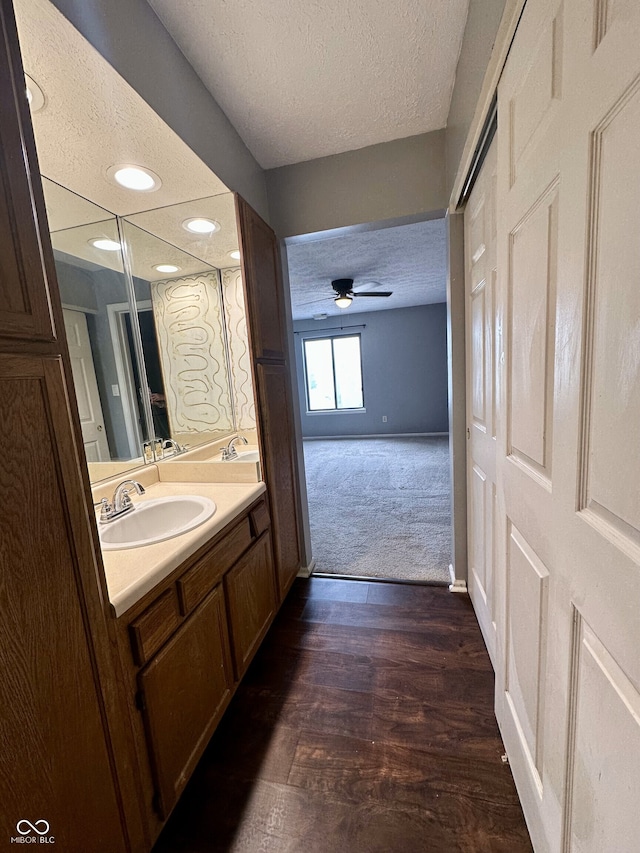 bathroom featuring ceiling fan, vanity, a textured ceiling, recessed lighting, and baseboards