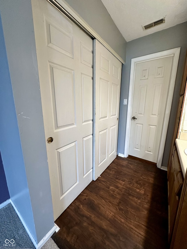interior space featuring visible vents, dark wood finished floors, baseboards, and a closet