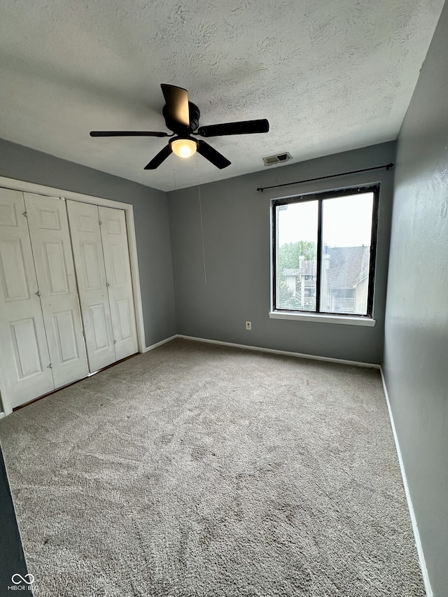 unfurnished bedroom featuring carpet floors, baseboards, visible vents, and a closet