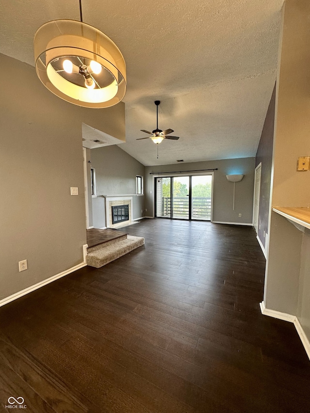 unfurnished living room featuring a textured ceiling, ceiling fan, a glass covered fireplace, and baseboards