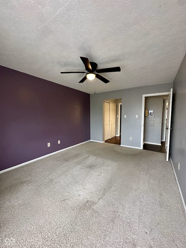 empty room with carpet floors, a textured ceiling, ceiling fan, and baseboards