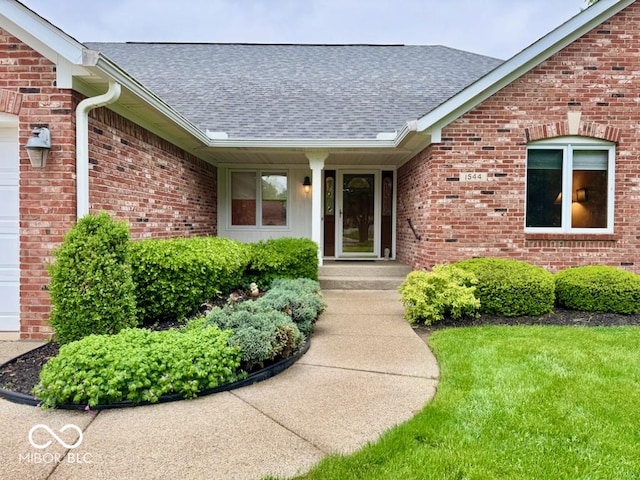 entrance to property with roof with shingles and brick siding