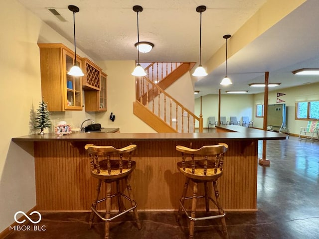 indoor bar with concrete floors, stairway, and hanging light fixtures