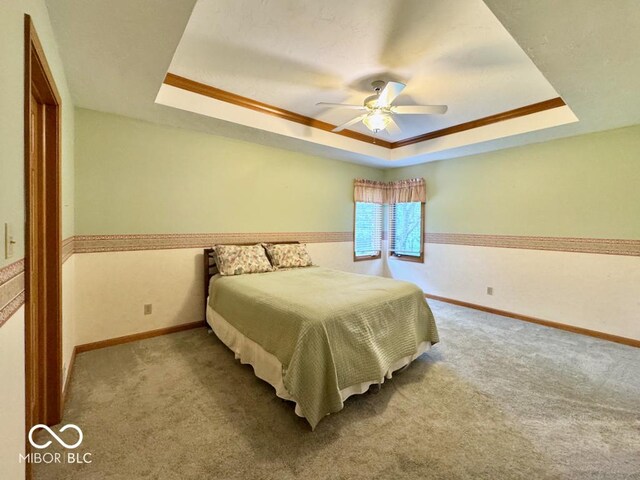 carpeted bedroom featuring a raised ceiling, baseboards, and a ceiling fan