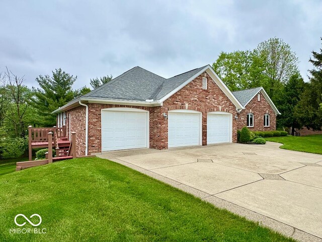 view of front of house featuring a garage, driveway, a front lawn, roof with shingles, and brick siding