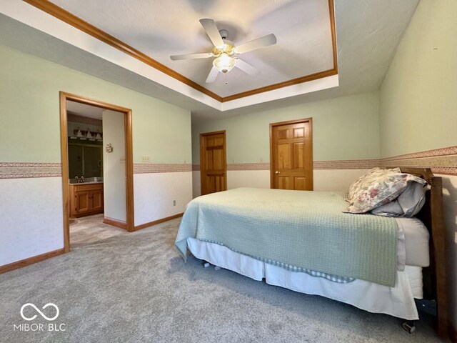 bedroom featuring a tray ceiling, carpet, crown molding, connected bathroom, and baseboards