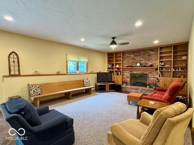 carpeted living area with ceiling fan, built in features, recessed lighting, a brick fireplace, and baseboards