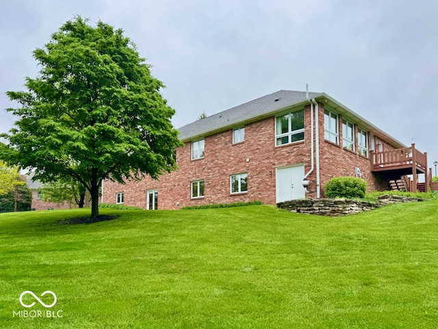 back of house with a yard, brick siding, and a deck